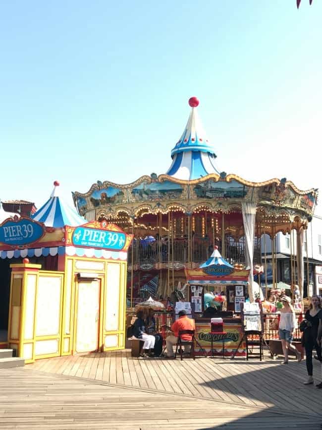 Carousel and people walking on boardwalk at Pier 39 in San Francisco