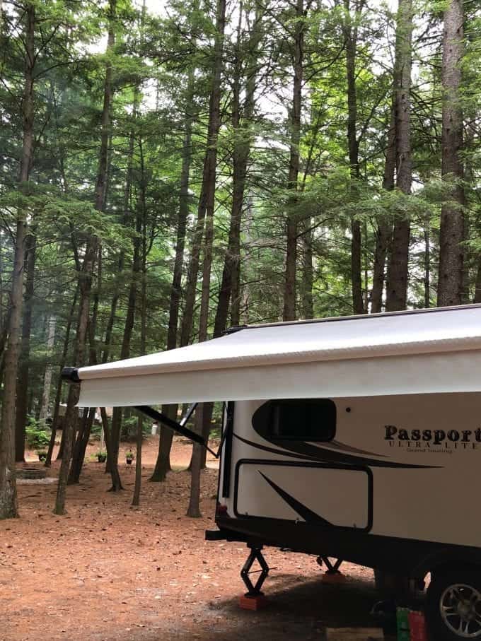 Close up of ivory colored awning on travel trailer parked at campsite.