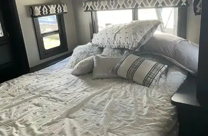 Bed inside RV with pile of pillows.