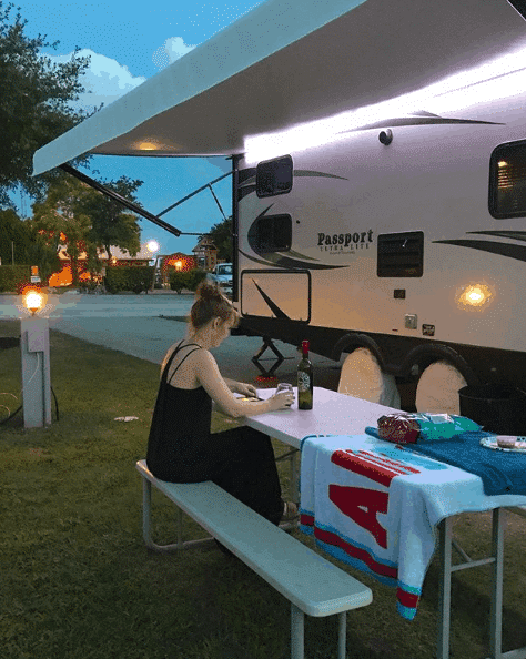 Woman reading at campsite at night considering the hard things about living full time in RV