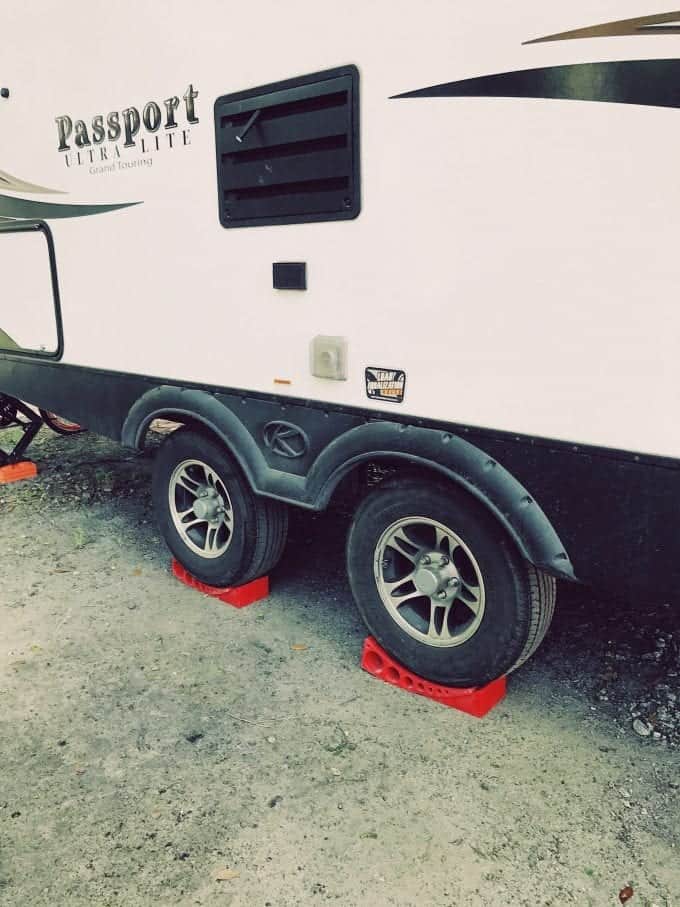 Bright red Andersen Leveler wedges used under travel trailer tires.