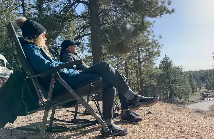 Man and woman relaxing outdoors on camping rocking chairs