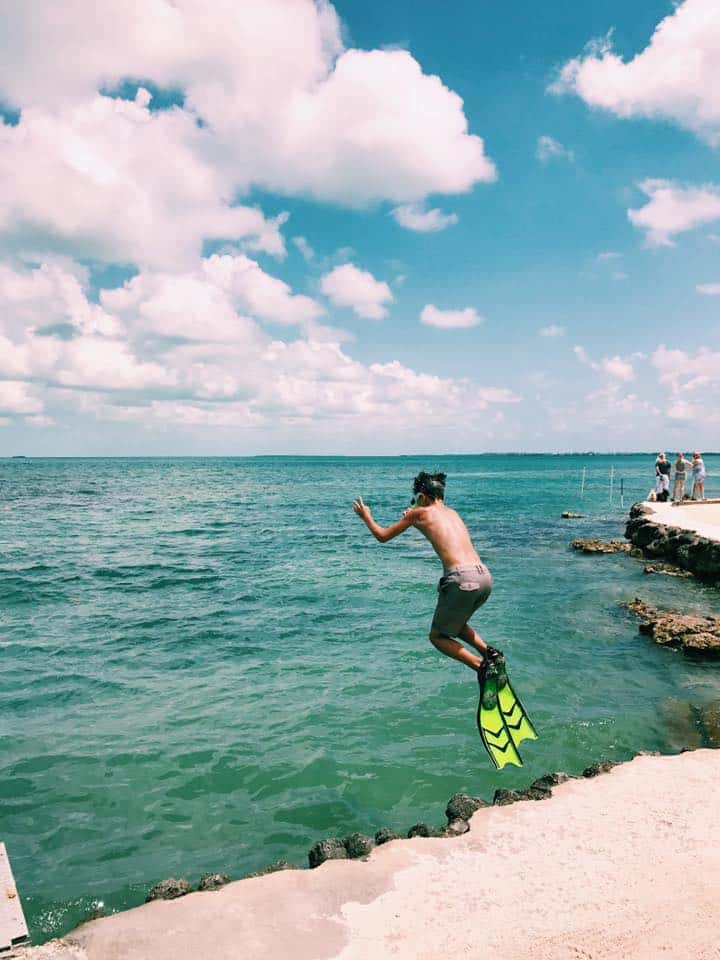 Boy with flippers jumping into ocean at Florida Keys.