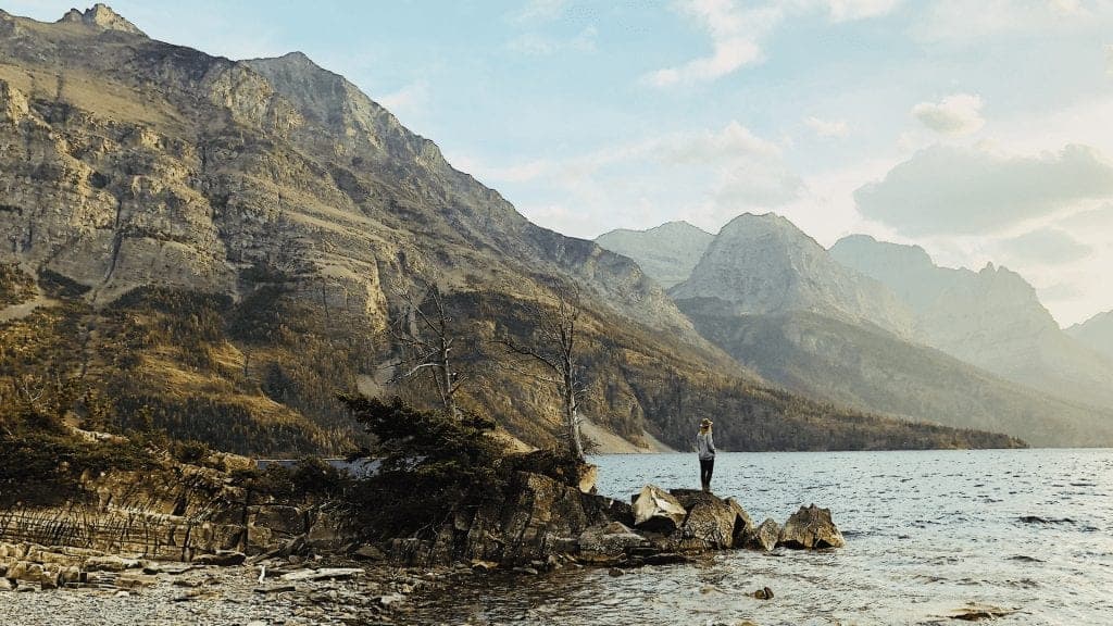 Woman stands on edge of lake in Glacier National Park