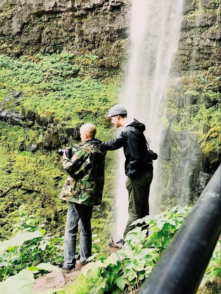 Two men standing near waterfall in Oregon