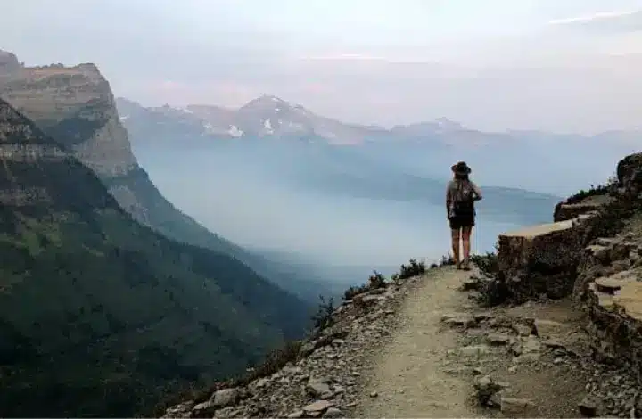 Woman wearing hat hiking Highline Trail in Glacier National Park