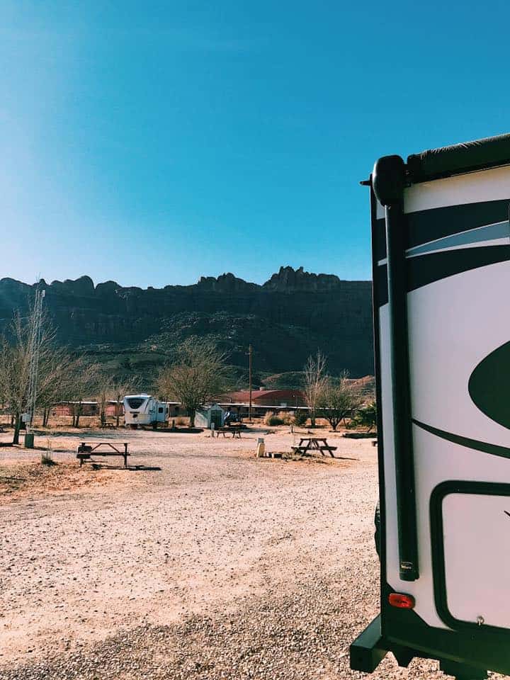 Rear edge of RV parked in open area campground.