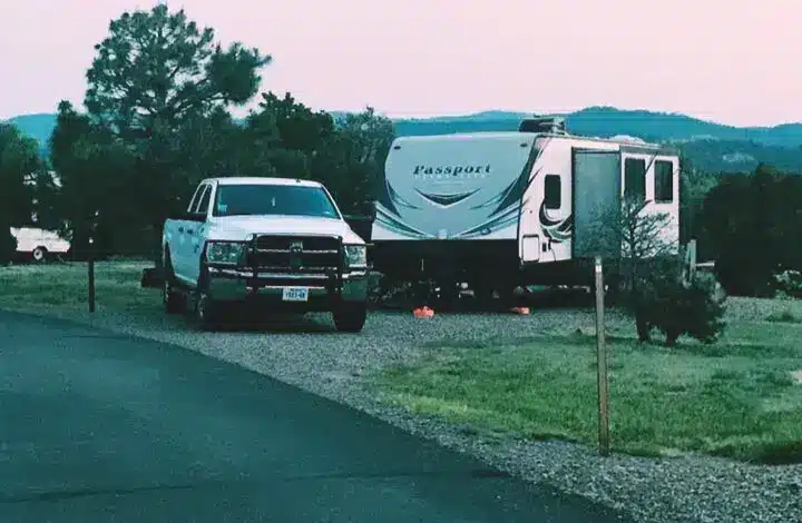 White truck and travel trailer parked at campsite.