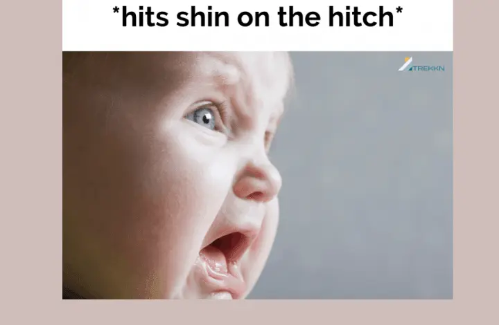 Close up of baby crying with text 'hits shin on hitch'