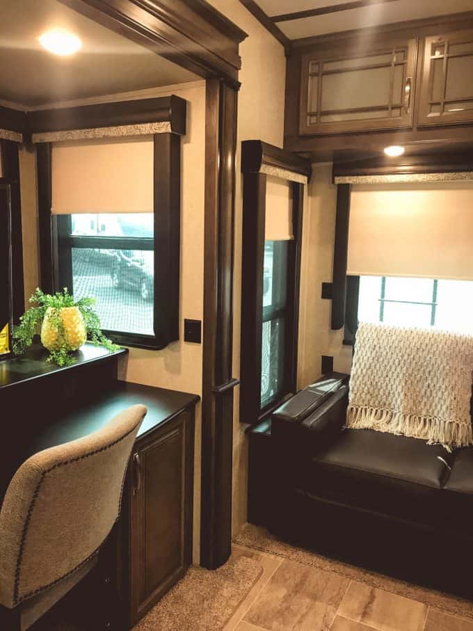 Desk chair and sofa near windows inside Keystone Montana RV