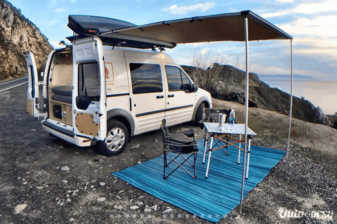 Camper van and awning set up above picnic area in California