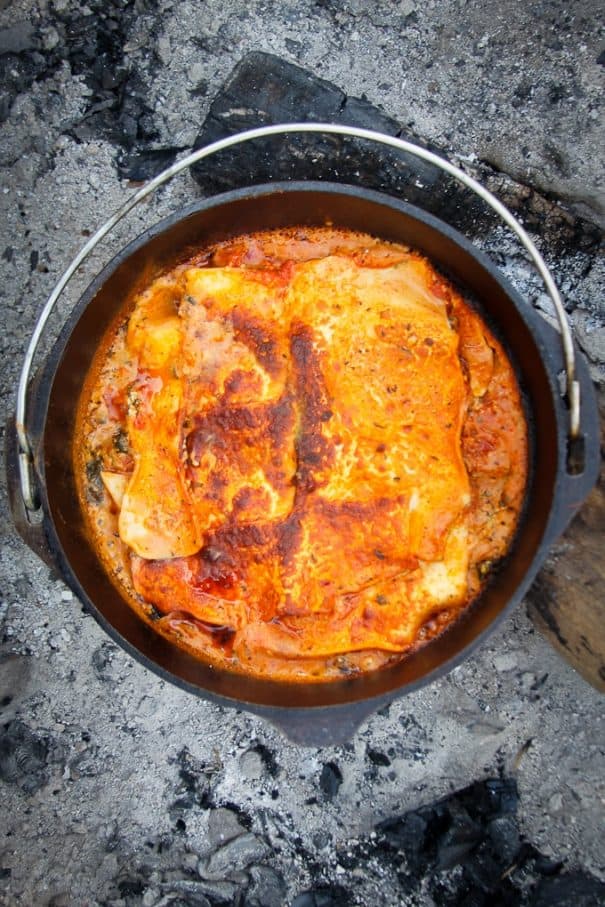 Vegetarian lasagna cooking in dutch oven over campfire