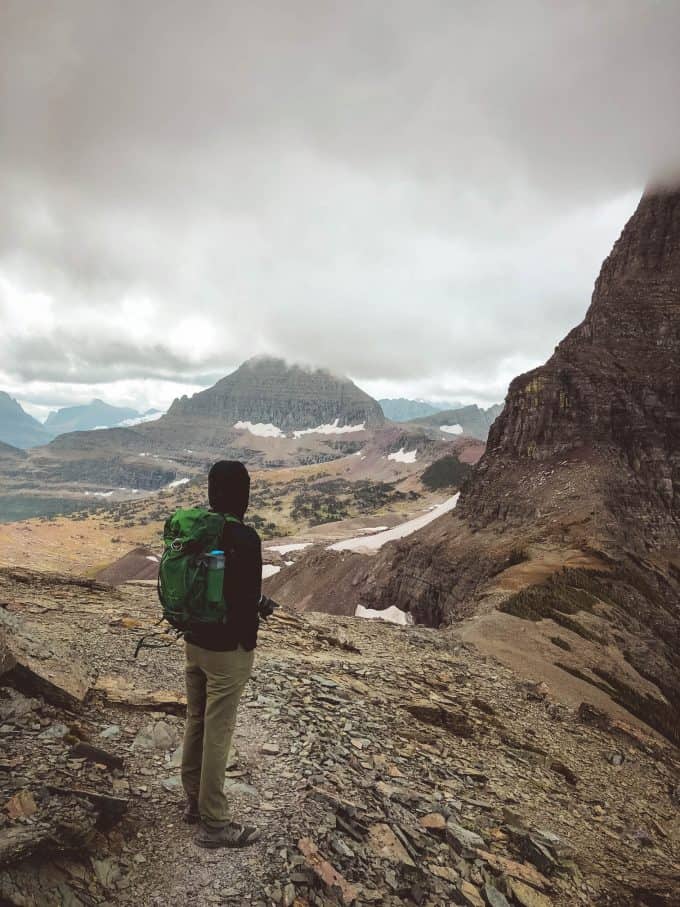 Male hiker standing on mountain ridge with a wide view of Glacier National Park