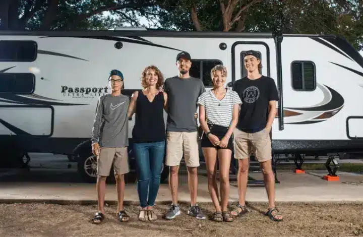 Family of 5 standing in front of the travel trailer they live in full time.