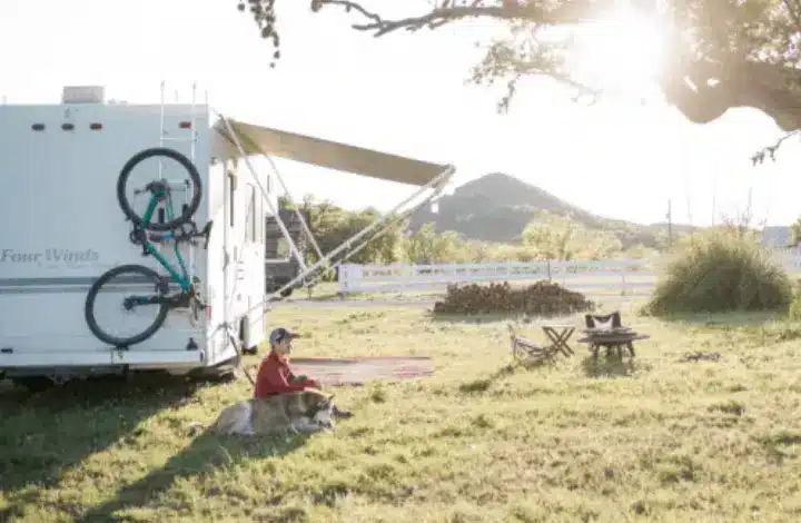 Boy and dog sitting next to travel trailer at rv park in Austin