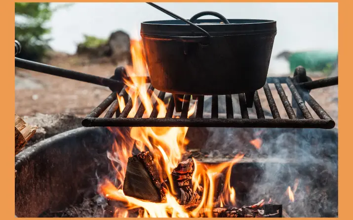 Dutch oven on grill set over open campfire.