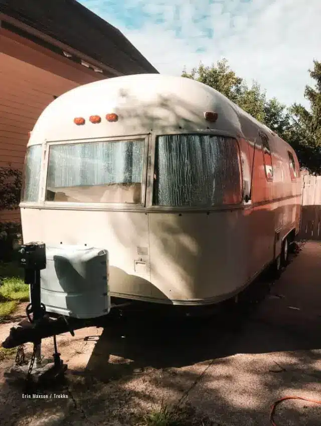 White Airstream parked in front of house.