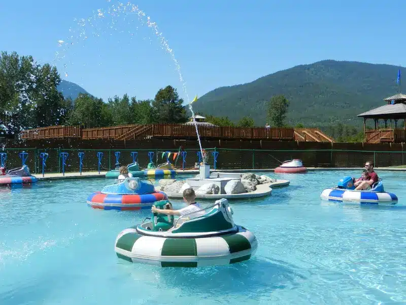 Kids and adults on inflatable bumper cars at amusement park.