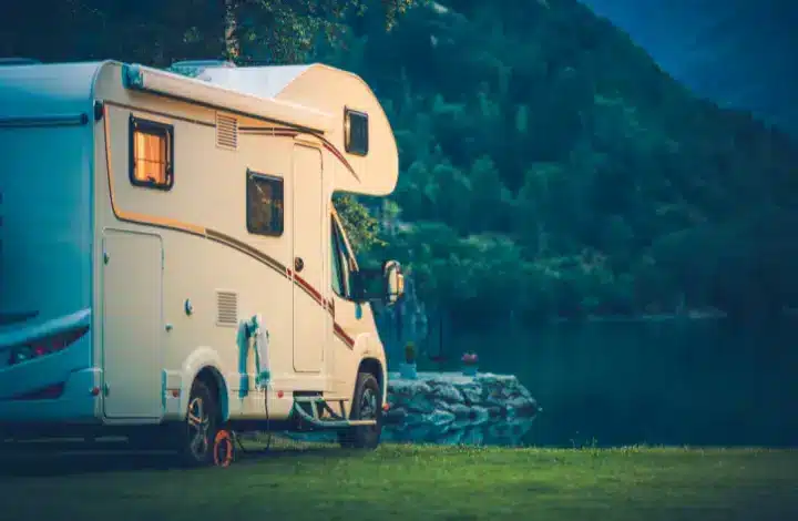 Motorhome RV parked on grass near lake at dusk