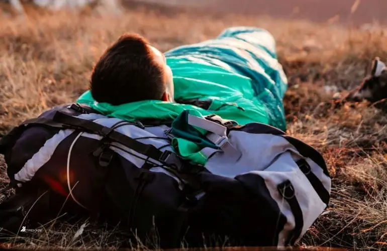 Man resting outdoors in sleeping bag.