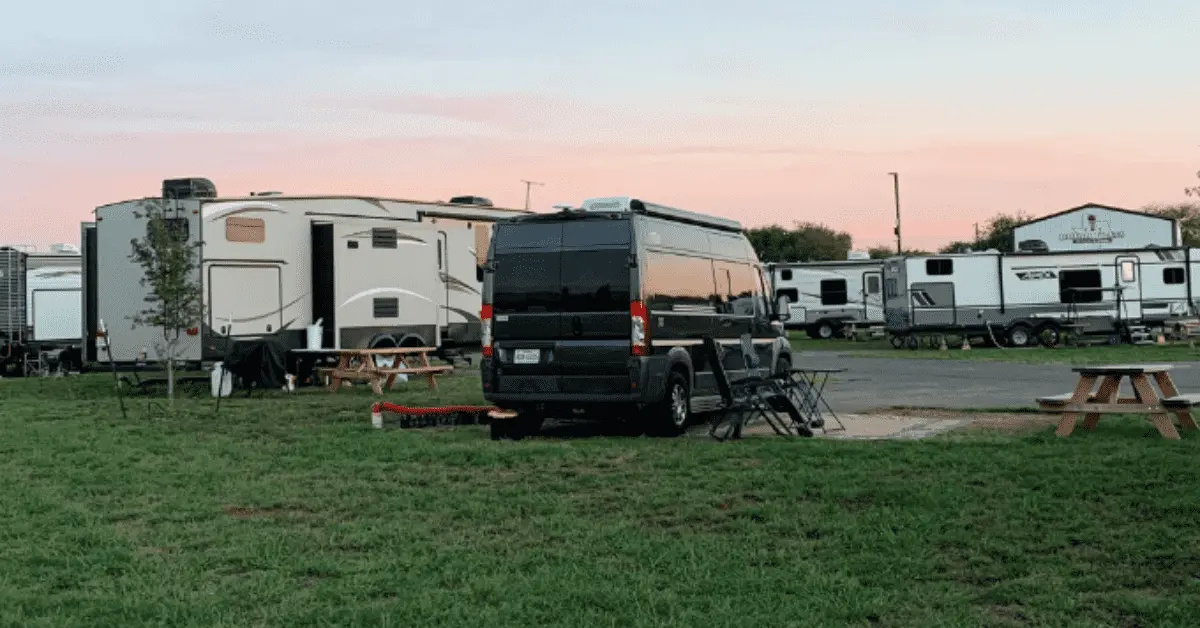 Black campervan parked near picnic table at campsite