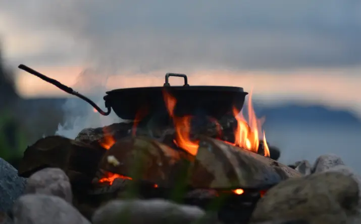 Camping meal cooking in one pot on grill over campfire.