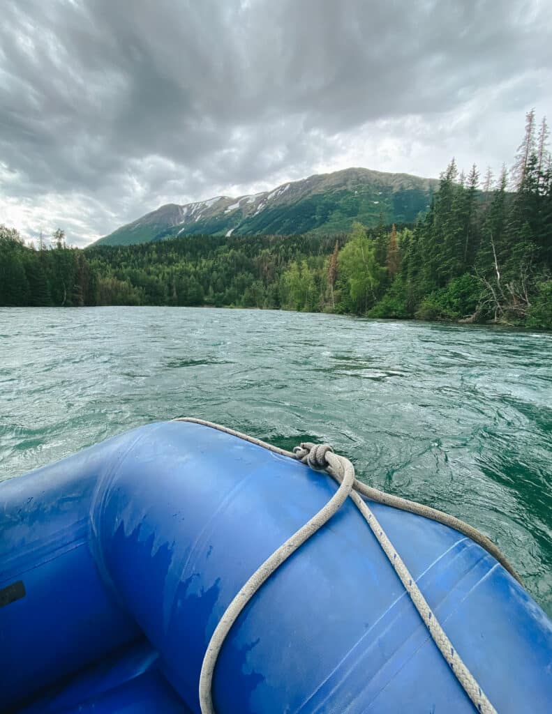 Front of blue raft on Kenai River with view of mountains ahead