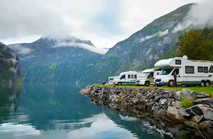 Multiple motorhome RVs parked at the best campsite near a beautiful lake.