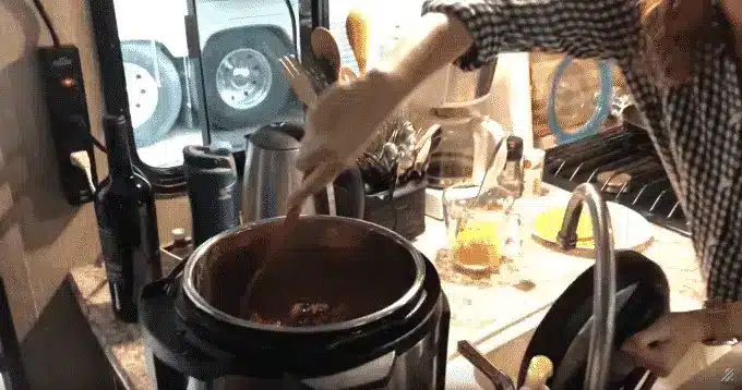 Close up of woman stirring contents of instant pot while cooking inside RV