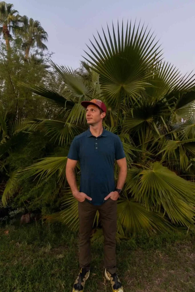 Man in hat and blue Kuhl hiking shirt standing in front of cactus