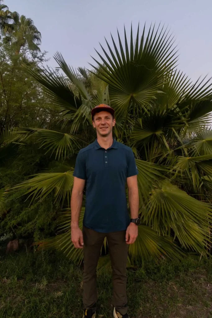 Man in hat and blue Kuhl hiking shirt looking back at camera