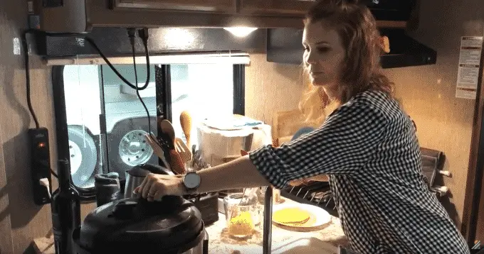 Woman inside RV opening the lid to an instant pot