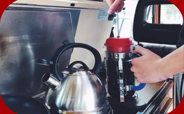 Camper using a french press to make coffee in an RV