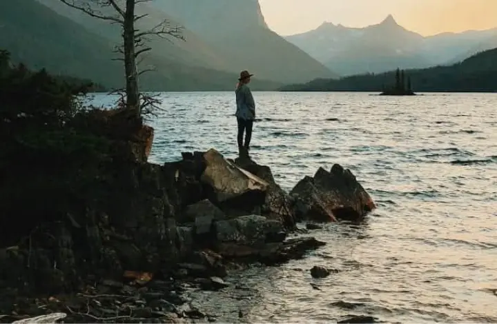 Woman stands on boulders at lake shore