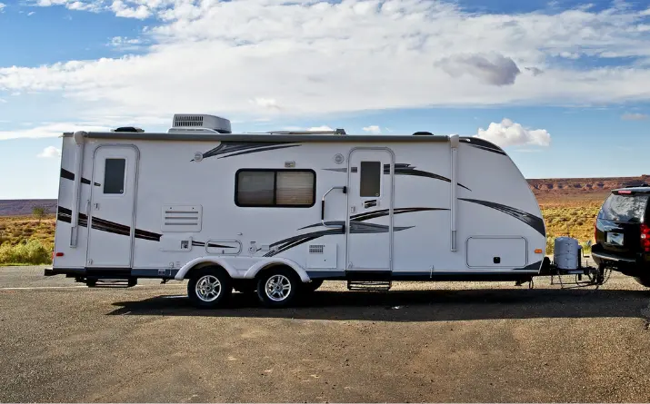 Travel trailer in front of boondocking area on clear sunny day.