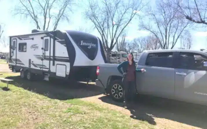 Woman standing near her truck and travel trailer.