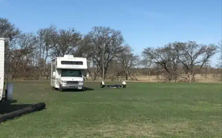 Class C RV stuck in a muddy grass field.